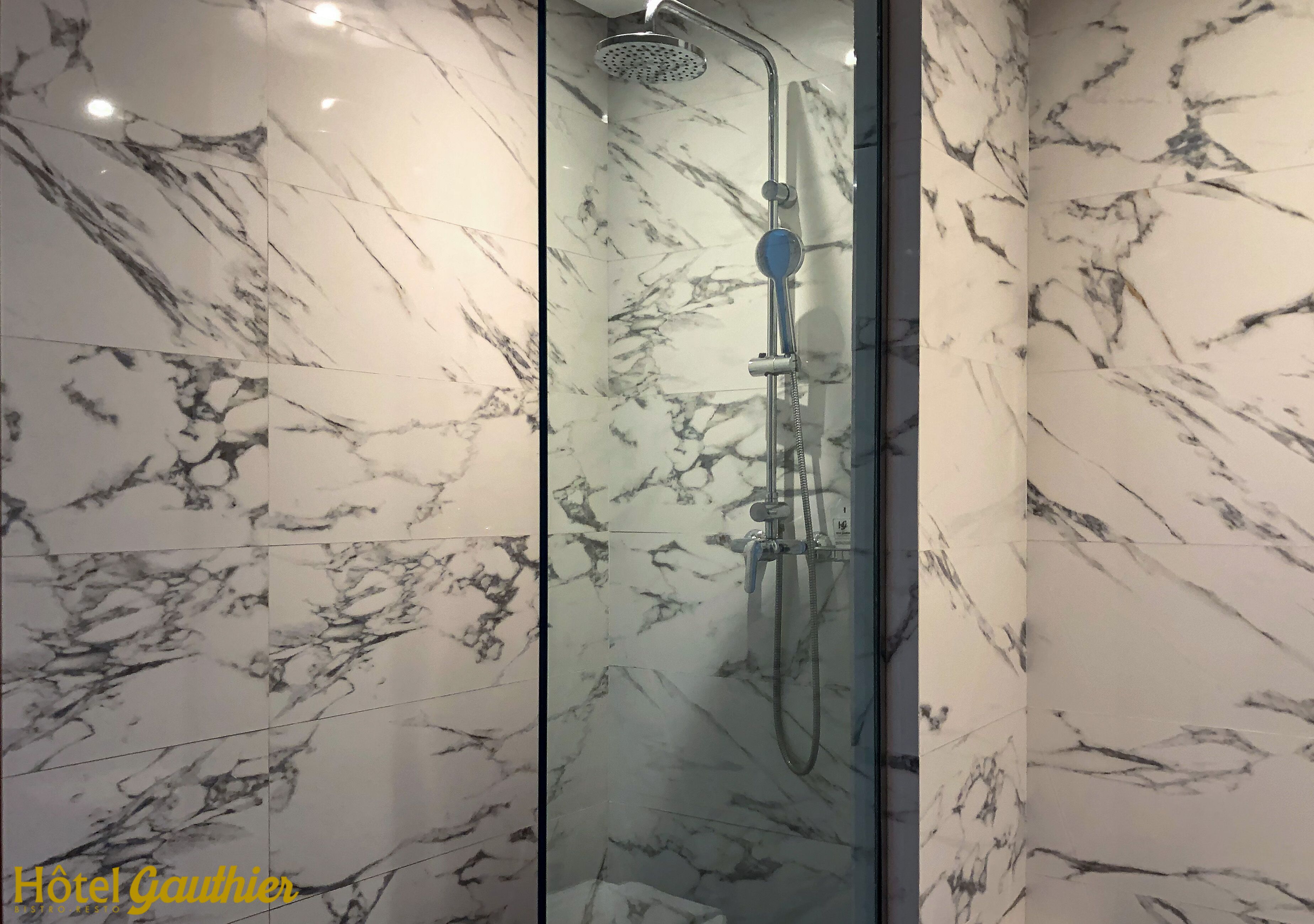 Un baño moderno con paredes de mármol y cabina de ducha con paredes de vidrio.