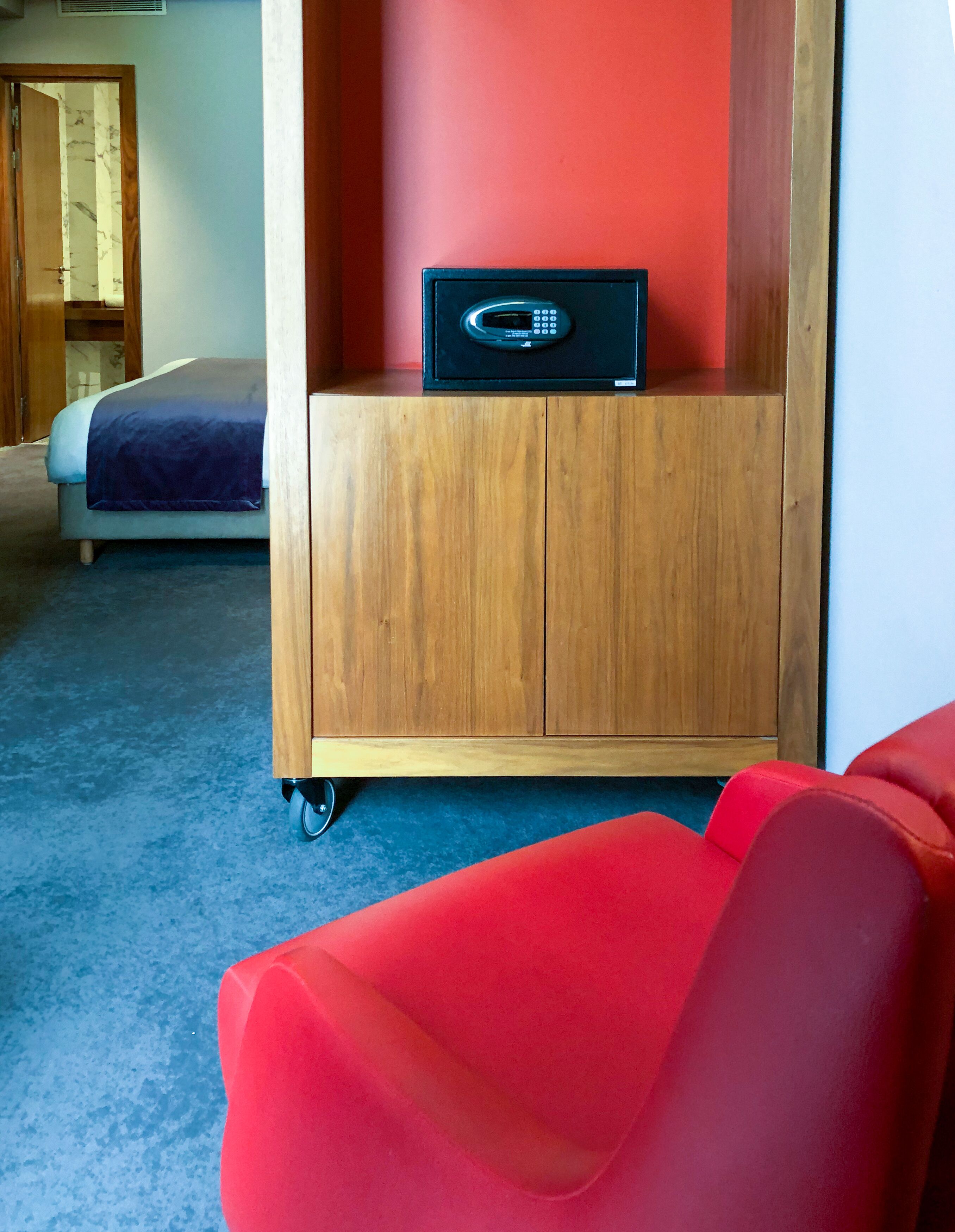 Ein Hotelzimmer mit einem Bett, einem Holzschrank mit einer Mikrowelle und einem roten Sessel.