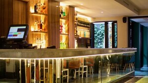 A modern bar area with a glass counter, wooden shelves with bottles, and a seating area with chairs. - Hôtel GAUTHIER (Casablanca)