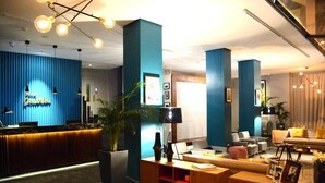 A modern hotel lobby with a reception desk, seating area, and a large potted plant. - Hôtel GAUTHIER (Casablanca)