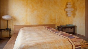 A bedroom with a large bed, a bedside table, a lamp, and a wall-mounted light fixture.