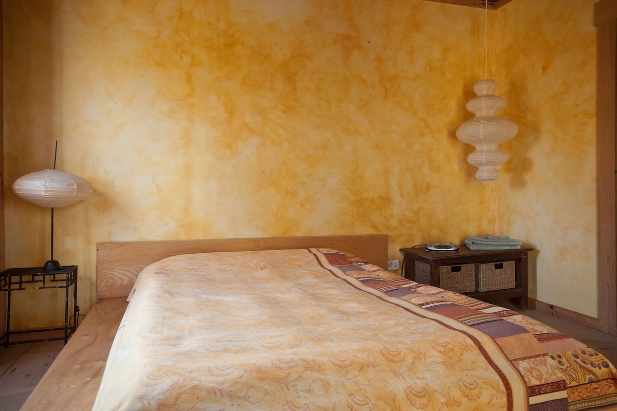 A bedroom with a large bed, a bedside table, a lamp, and a wall-mounted light fixture.
