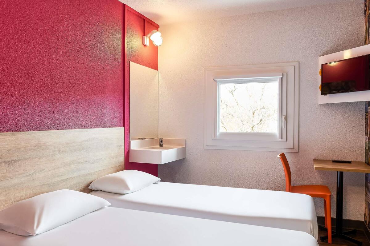 A room with a bed, a window, a sink, and a chair.