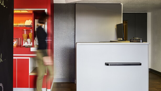 A modern kitchen with a red and white color scheme, a white countertop, and a built-in oven. - hotelF1 Lyon Sud Oullins (Oullins)