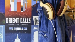 A denim jacket with headphones hanging on a wall adorned with various travel posters. - hotelF1 Lyon Sud Oullins (Oullins)
