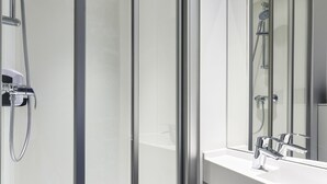 A modern bathroom with a glass shower enclosure, a white sink, and a large mirror. - hotelF1 Lyon Sud Oullins (Oullins)