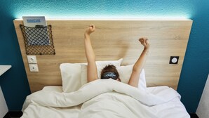 A bed with a wooden headboard, a white comforter, and a sign indicating a room number. - hotelF1 Lyon Sud Oullins (Oullins)