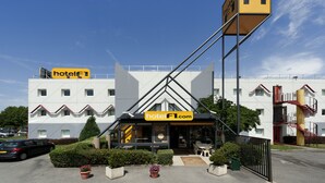 A hotel with a modern design, featuring a prominent 'hotel F1.com' sign, a well-maintained garden, and a clear sky. - hotelF1 Lyon Sud Oullins (Oullins)