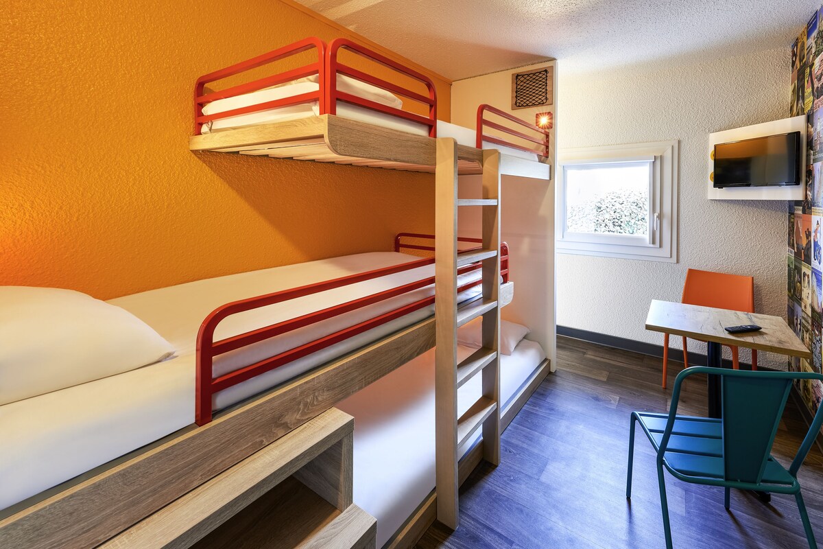 A bunk bed room with a desk and chair, a TV, and a window.
