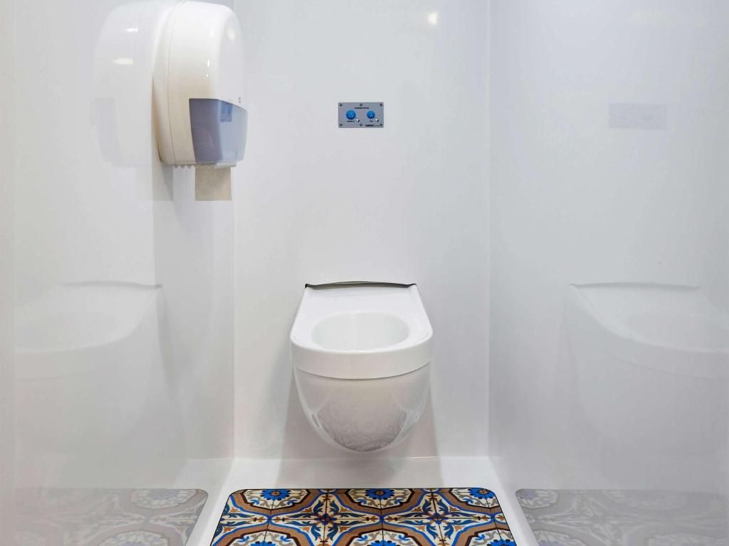 Eine Toilette mit Handtrockner und Bedienfeld an der Wand.