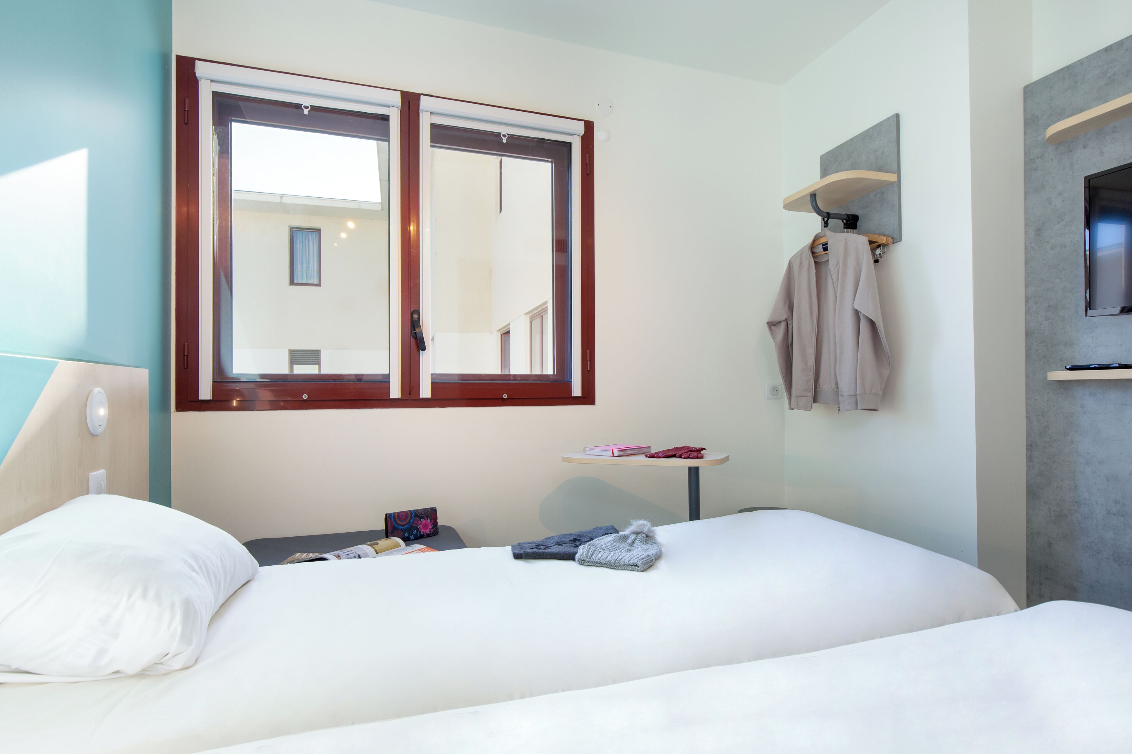 A hotel room with a large bed, a small table, a TV, and a window with a view of the outside.