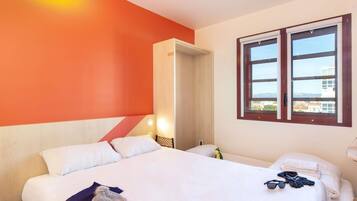 A hotel room with a large bed, a smaller bed, a window with a view, and a door leading to another room.