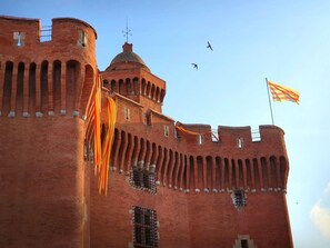 Un bâtiment historique en briques rouges, doté d’arcs au-dessus des fenêtres et surmonté d’un drapeau.