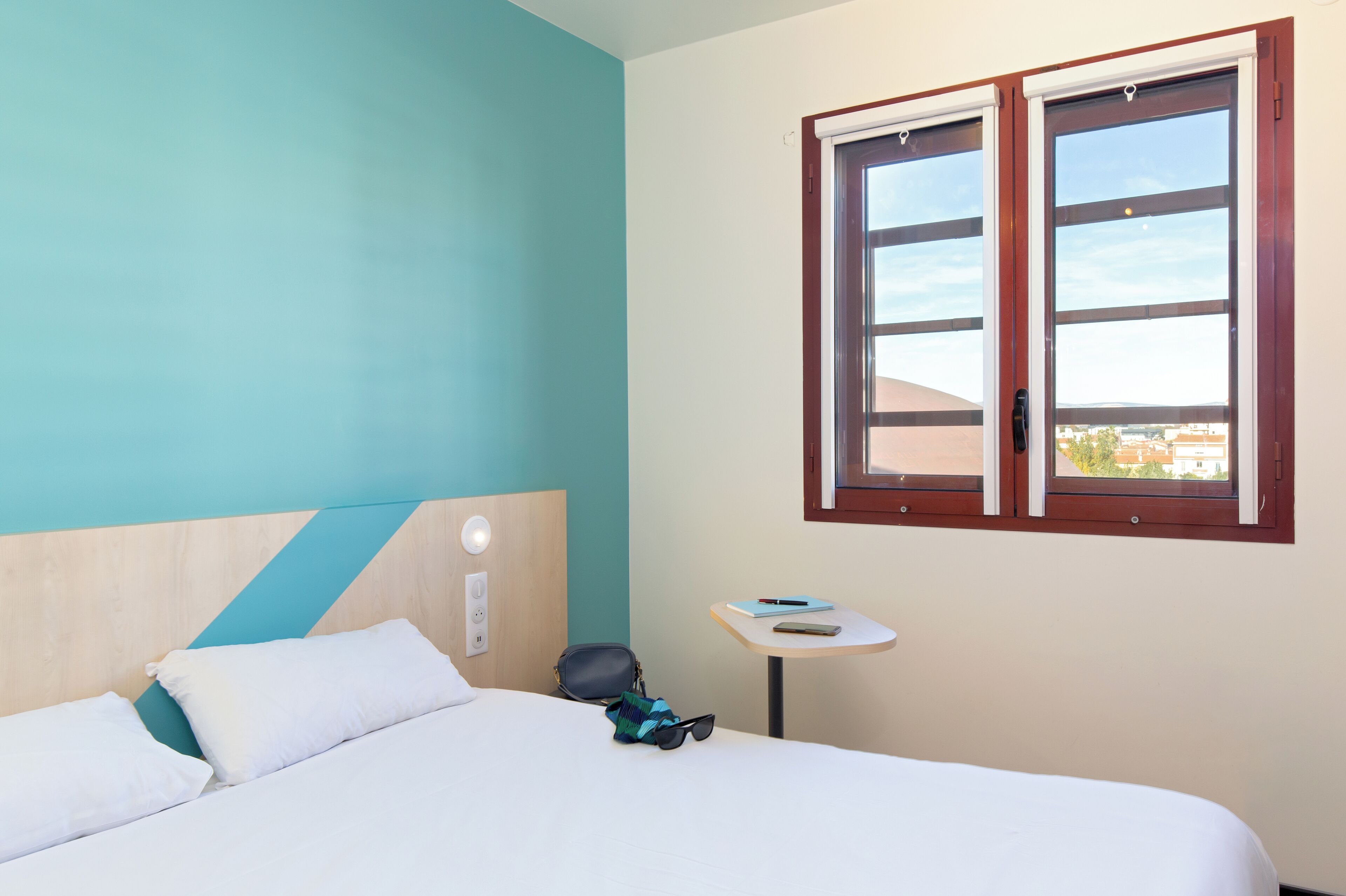 Una habitación de hotel con una cama, una mesita y una ventana con vistas.