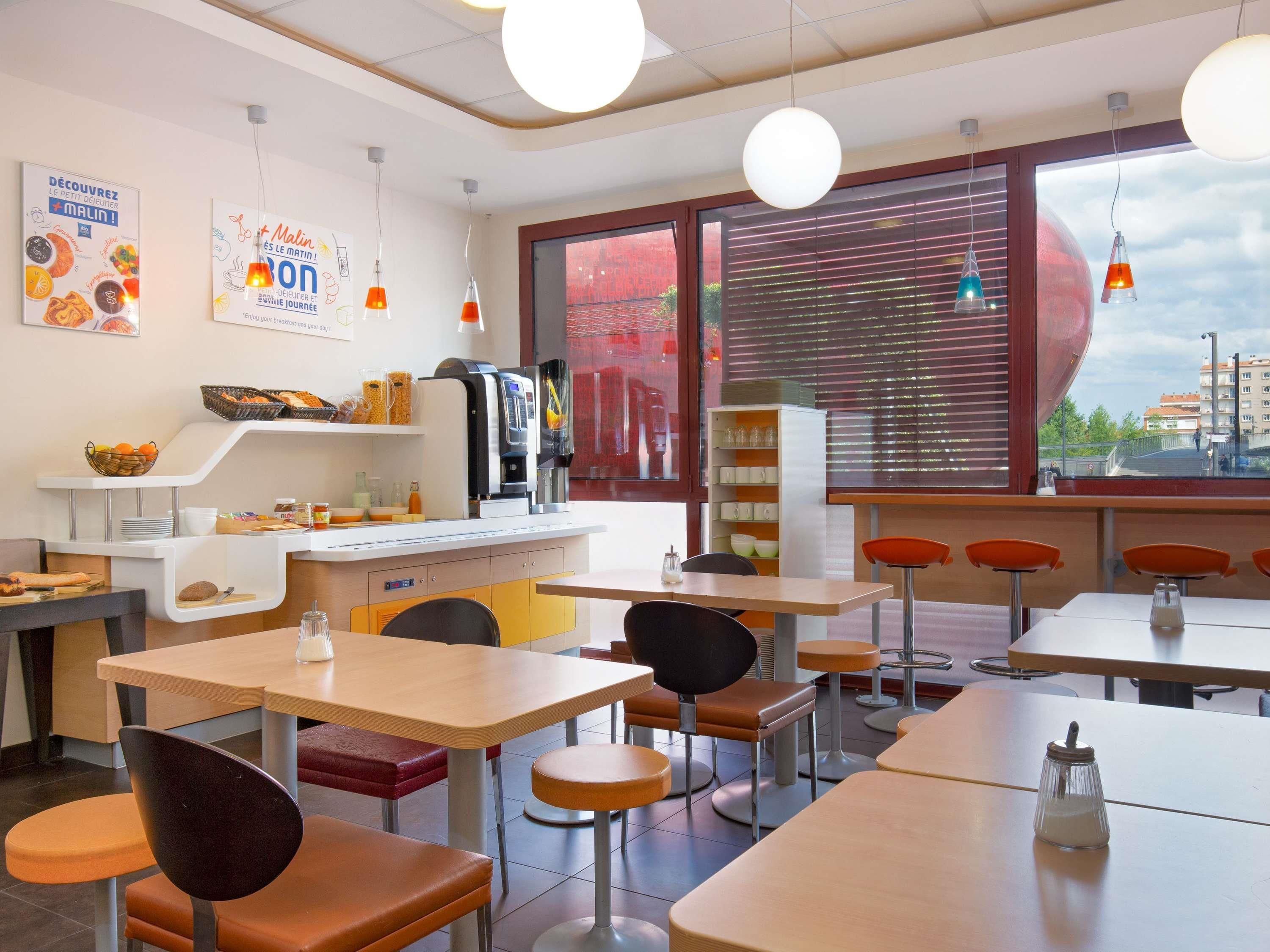 A modern dining area with tables and chairs, a coffee machine, and a window with a view.