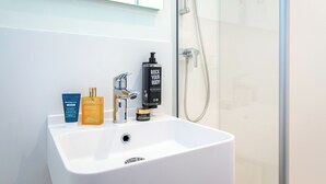 Un baño con un lavamanos blanco, un espejo y una ducha.