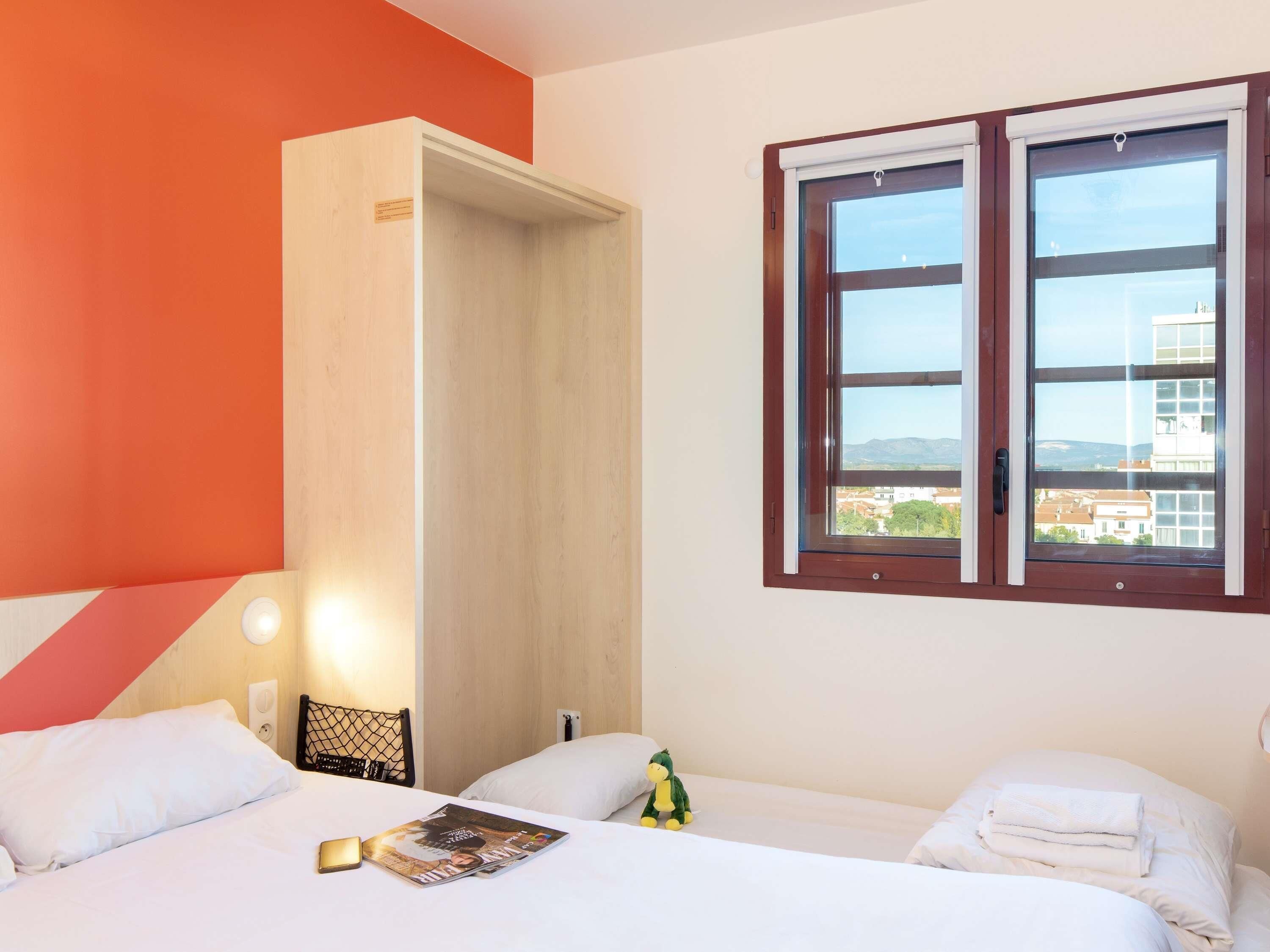 Une chambre d’hôtel avec un lit, une table de chevet, une fenêtre donnant sur un paysage agréable et une porte menant à un placard.