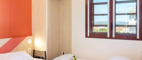 Une chambre d’hôtel avec un lit, une table de chevet, une fenêtre donnant sur un paysage agréable et une porte menant à un placard.