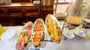 Un bufé de desayuno con diversas frutas y bollería.