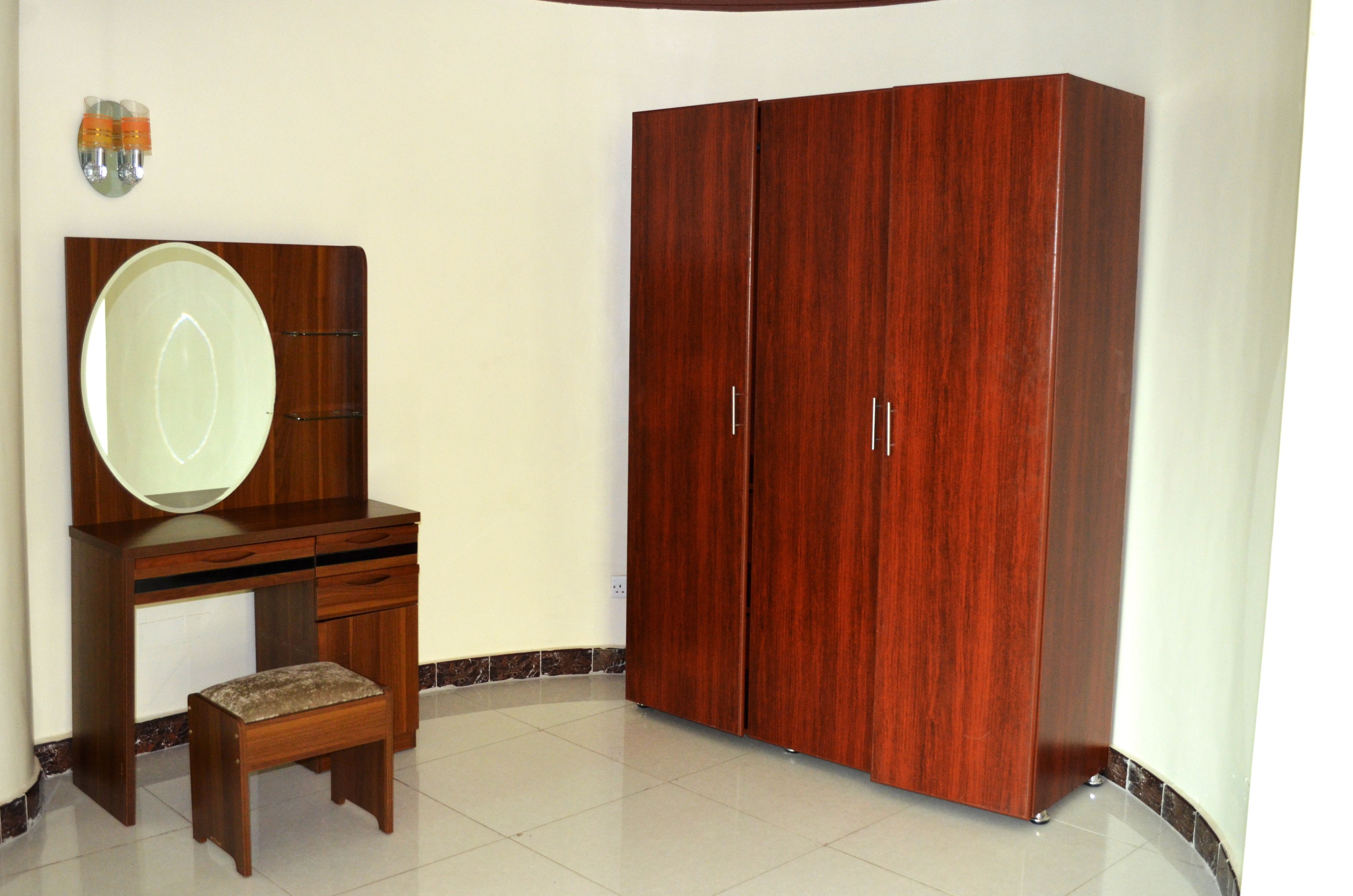 Una habitación con un escritorio de madera, un espejo grande y un armario.