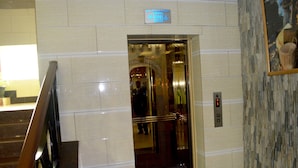 Un ascensor con un cartel que indica que es un ascensor, un pasamanos y un panel de control con botones.