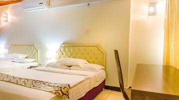 Habitación de hotel con dos camas, techo de madera, unidad de aire acondicionado y una mesita de noche.