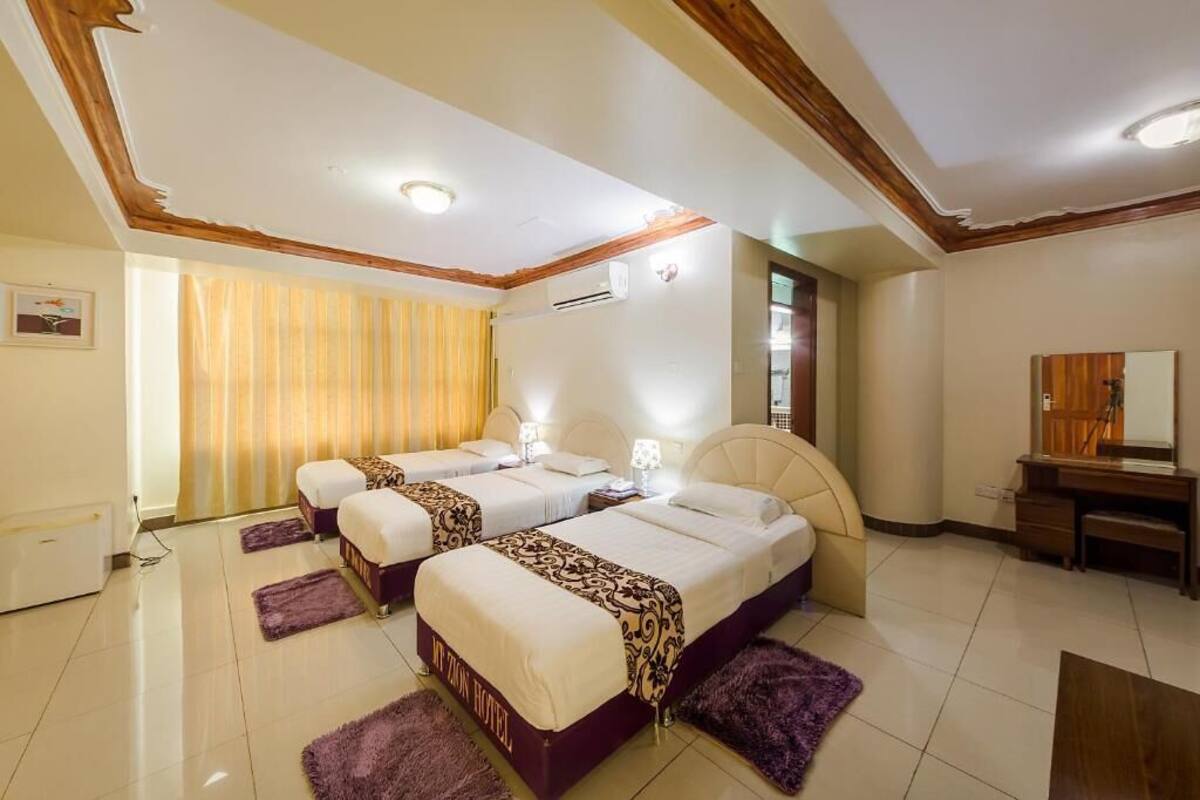 A hotel room with two beds, a desk, a chair, and a mirror.