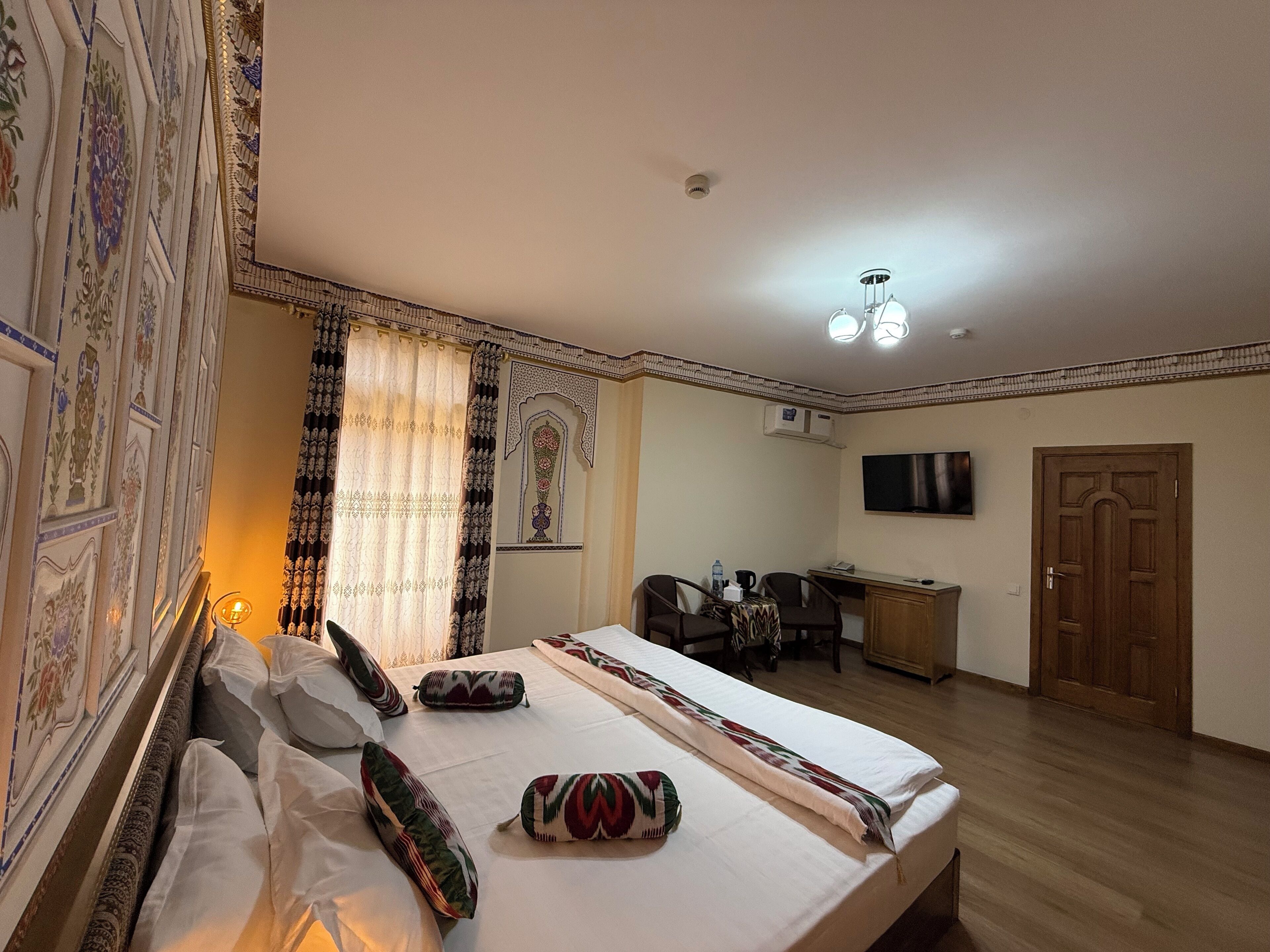 Ein Hotelzimmer mit einem großen Bett, einem Schreibtisch, einem Sessel, einem Fernseher und einer Tür.