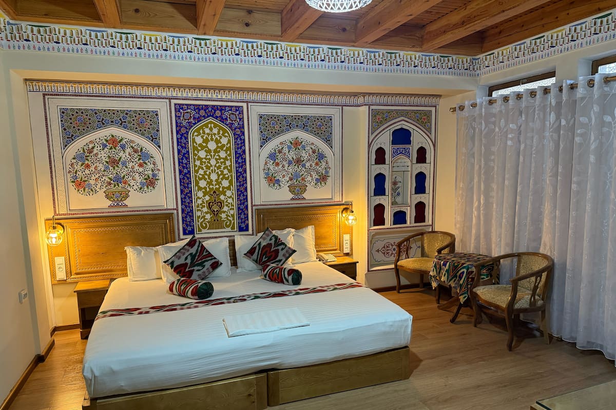 Ein Schlafzimmer mit einem großen Bett, zwei Nachttischen, einem Sessel und einem kleinen Tisch.