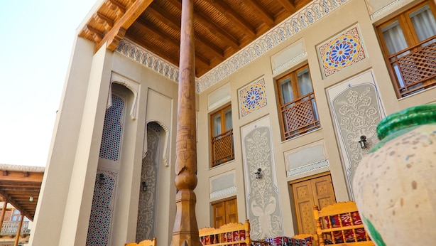 A traditional interior with wooden furniture and patterned walls. - Hotel Fatima (Bukhara)