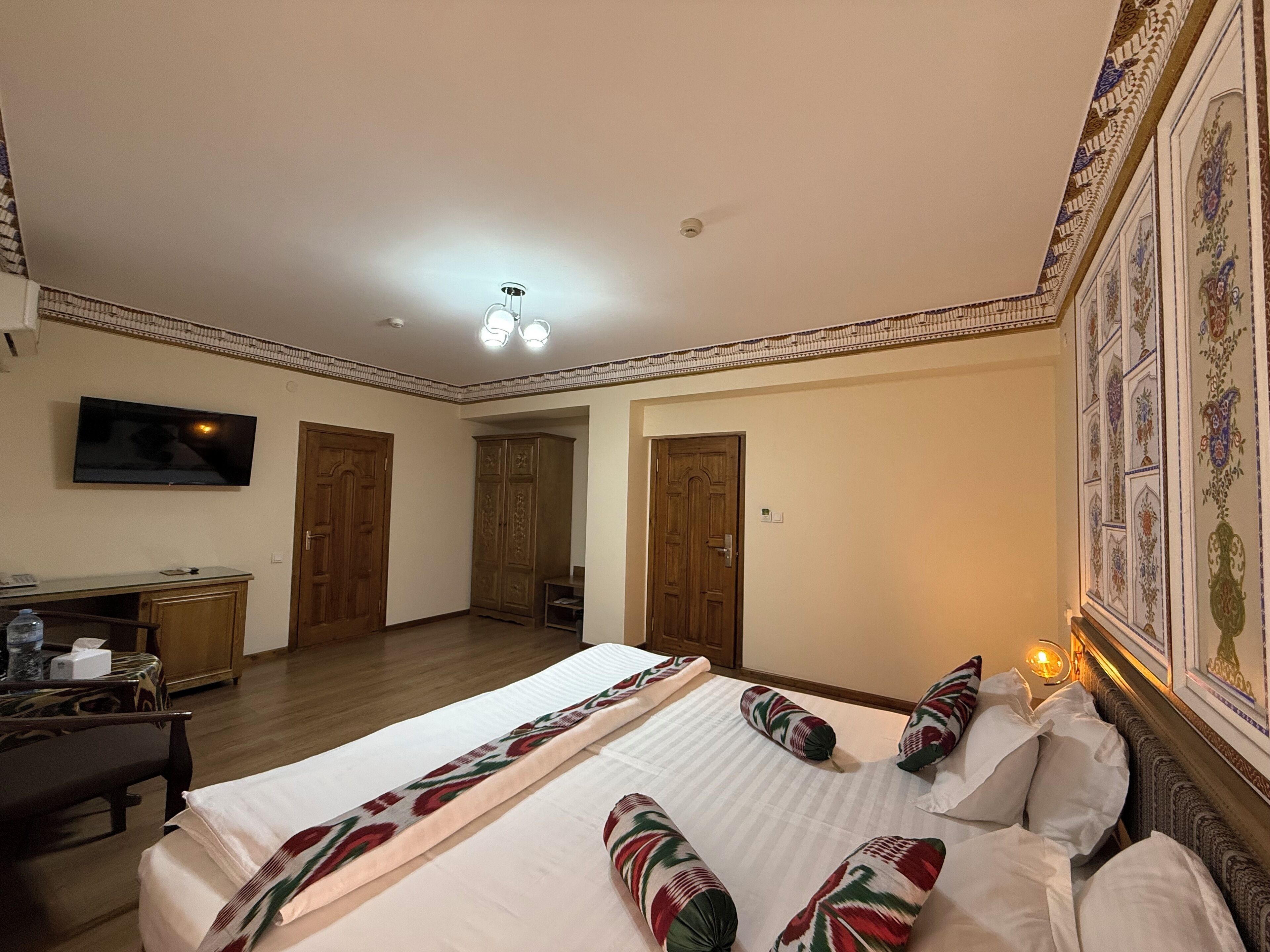 A hotel room with a large bed, a desk, a television, and a wardrobe.