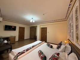 Una habitación de hotel con una cama grande, un escritorio, un televisor y un armario.