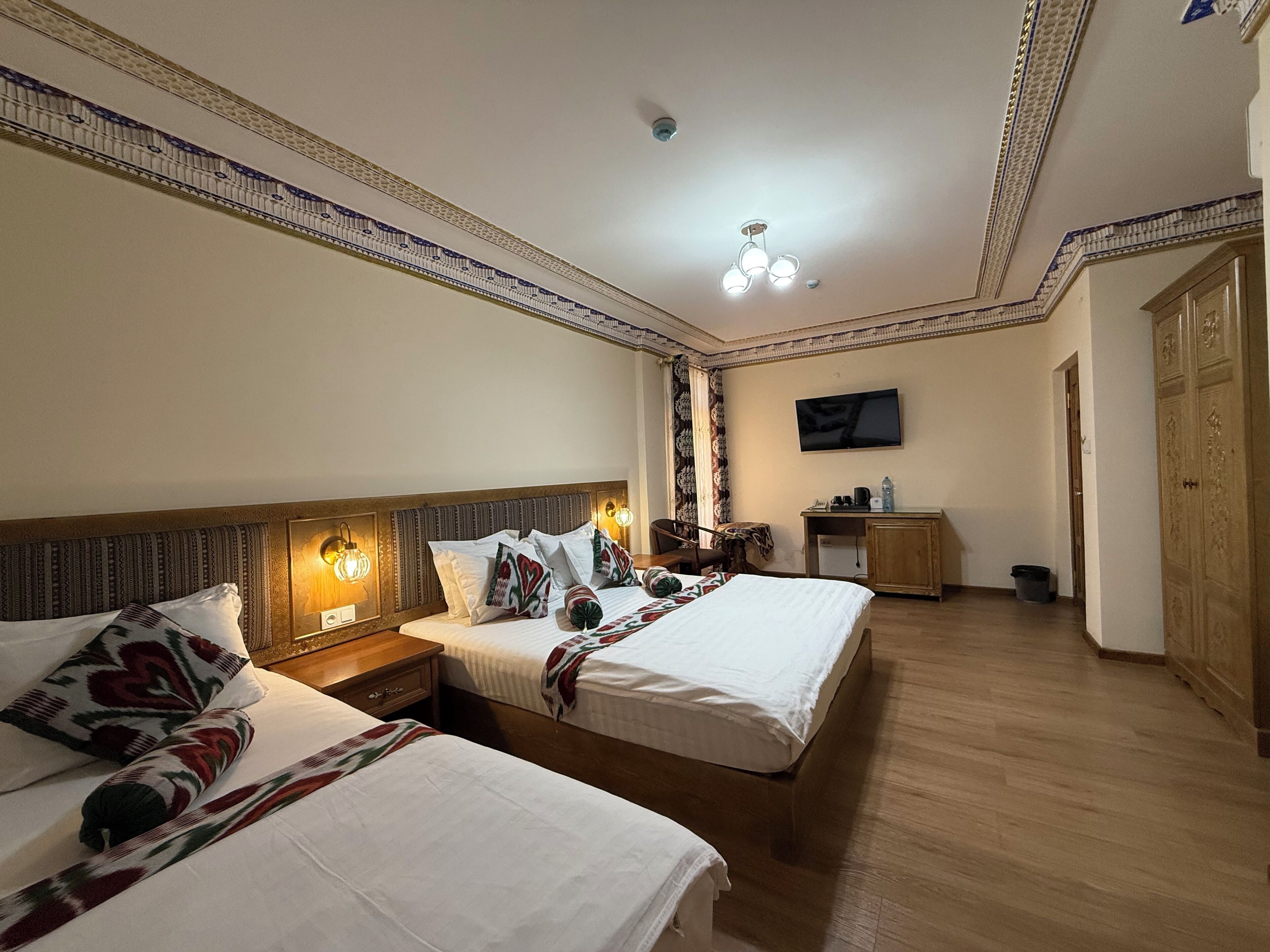 A hotel room with two beds, a TV, a desk, and a wardrobe.