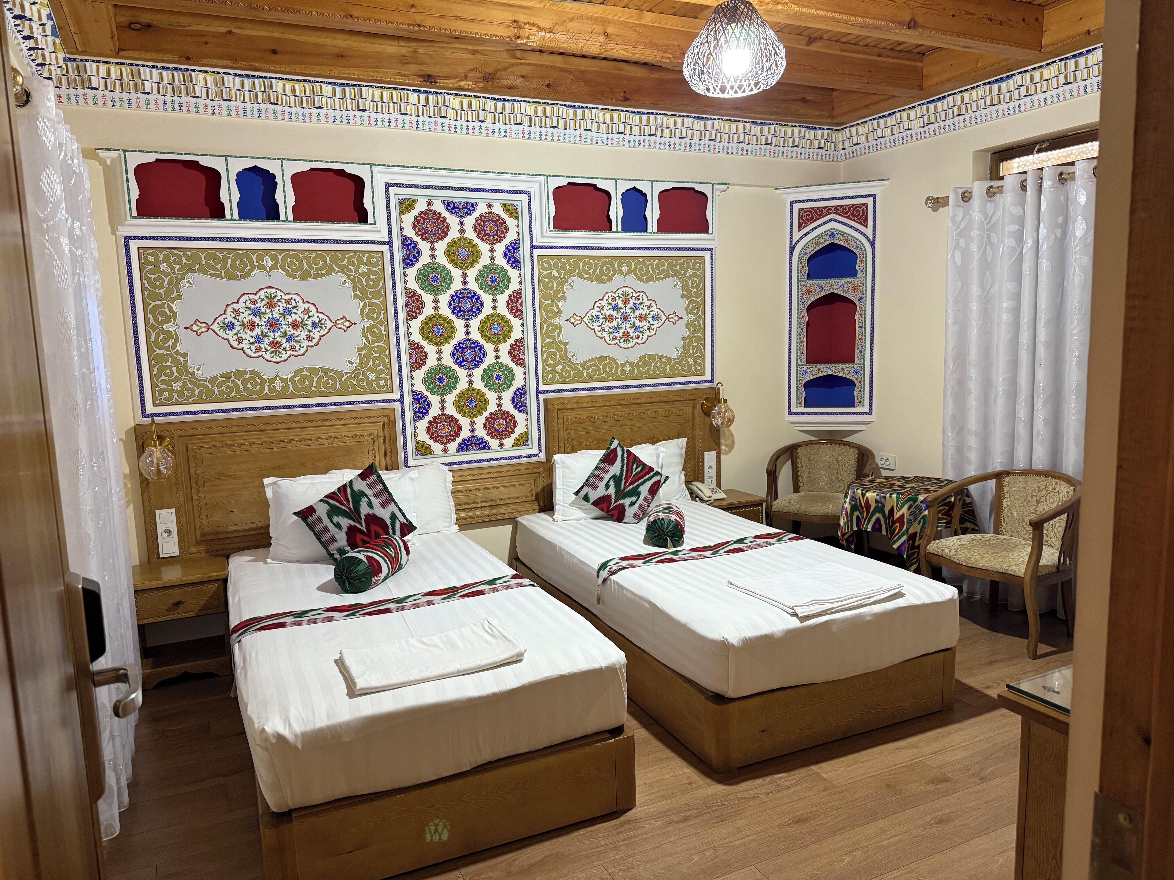 A hotel room with two beds, a wooden ceiling, and decorative wall panels.
