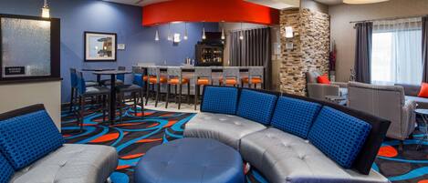 Un vestíbulo de hotel con una zona de estar curvada, un bar y un centro de negocios.