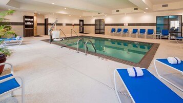 Zona de piscina de hotel con sillas de descanso, vestuario y mostrador de recepción.
