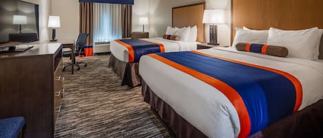 A hotel room with two beds, a desk, a chair, a TV, and a window with curtains.