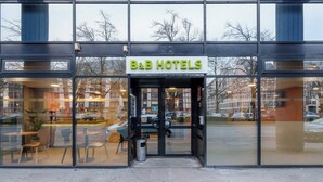 The exterior of B&B Hotels with a glass entrance, a visible parking area, and a reflection of the surrounding buildings. - B&B HOTEL Troyes Centre (Troyes)