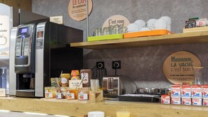A breakfast bar with a coffee machine, jars of jam, and a tray of croissants and juice. - B&B HOTEL Troyes Centre (Troyes)