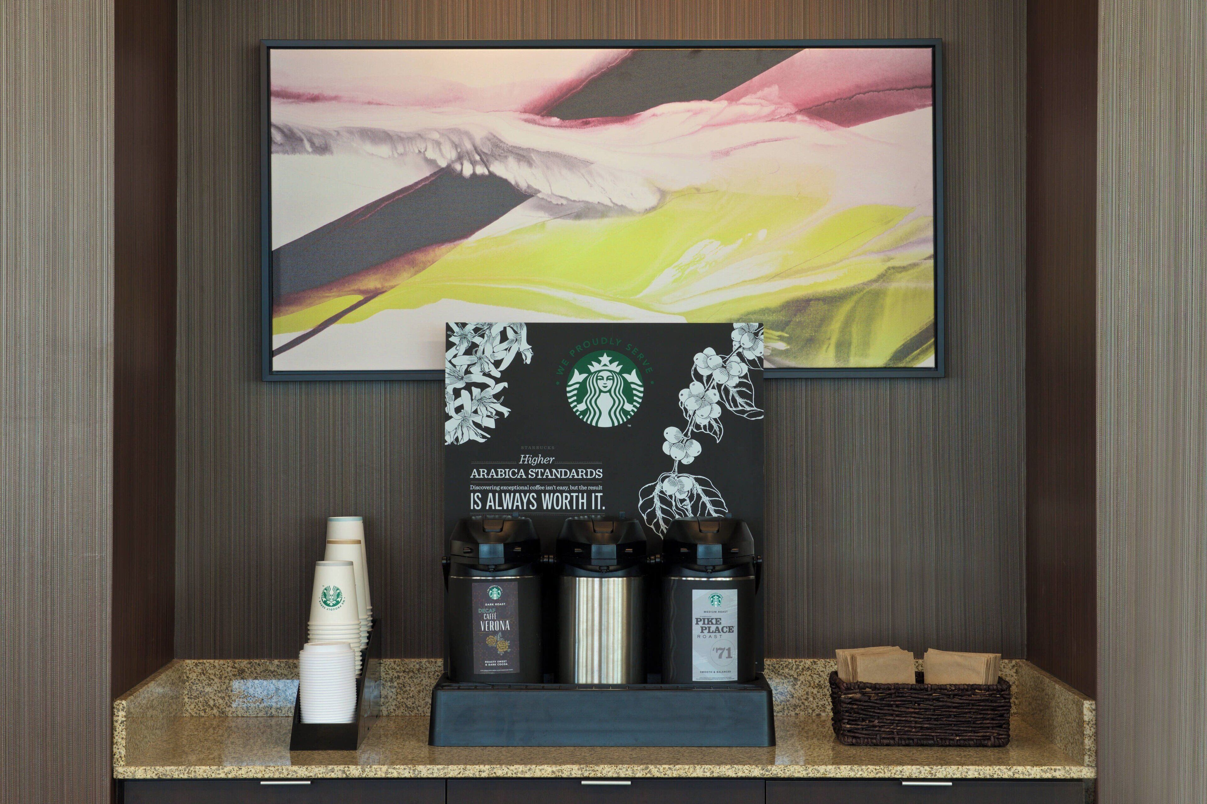 A coffee station with Starbucks branded coffee makers and disposable cups.