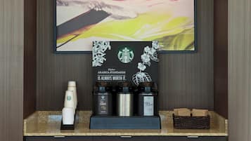 A coffee station with Starbucks branded coffee makers and disposable cups.