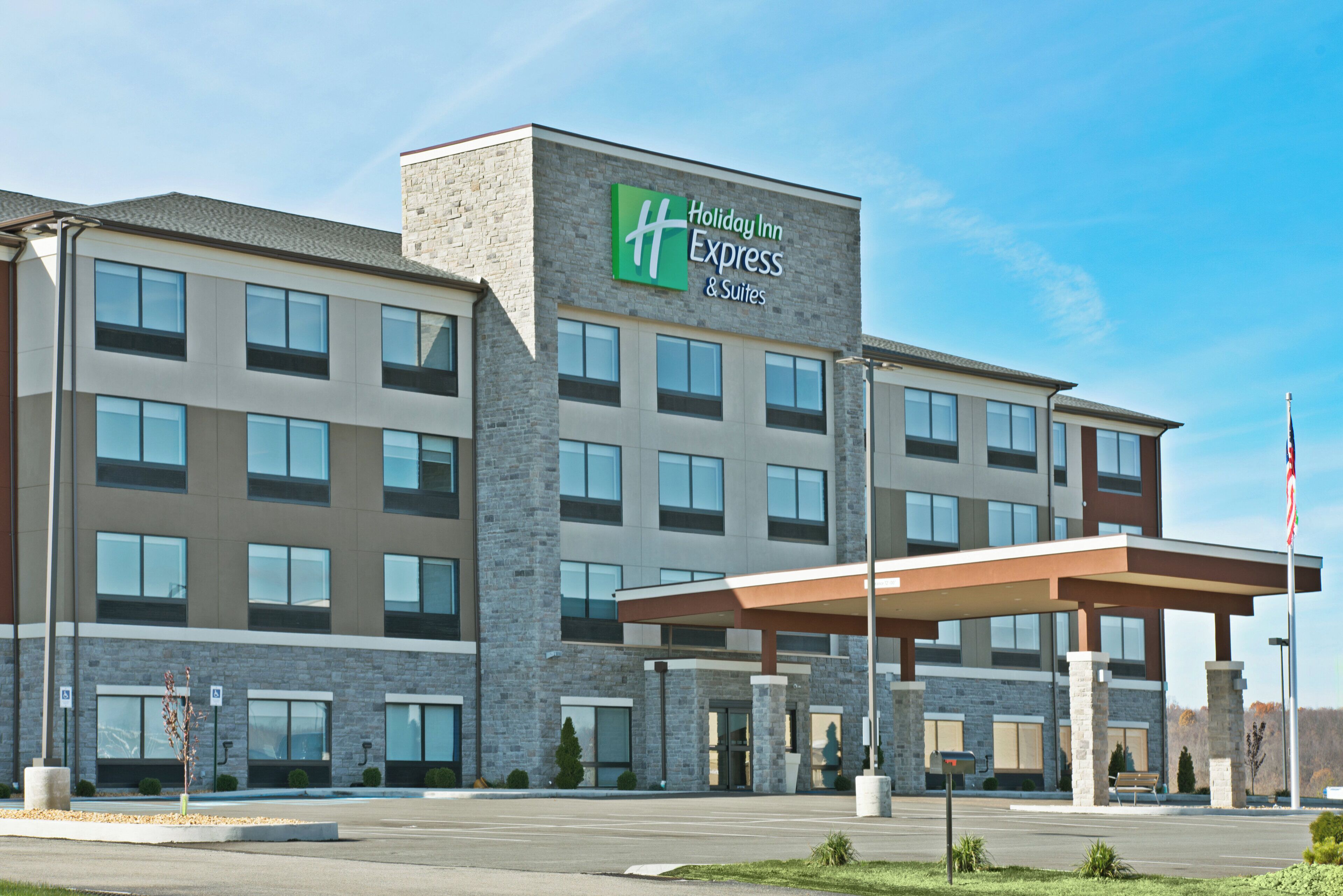 A Holiday Inn Express & Suites hotel with a stone facade, multiple windows, and a covered entrance.