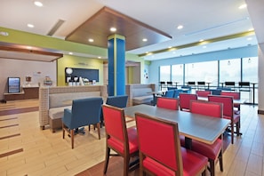 A modern restaurant with booths and tables, a coffee station, and a view through large windows. - Holiday Inn Express & Suites Uniontown by IHG (Uniontown)