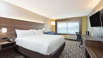 Quarto de hotel com uma cama grande, uma escrivaninha, uma cadeira, televisão de tela plana e janela com vista.