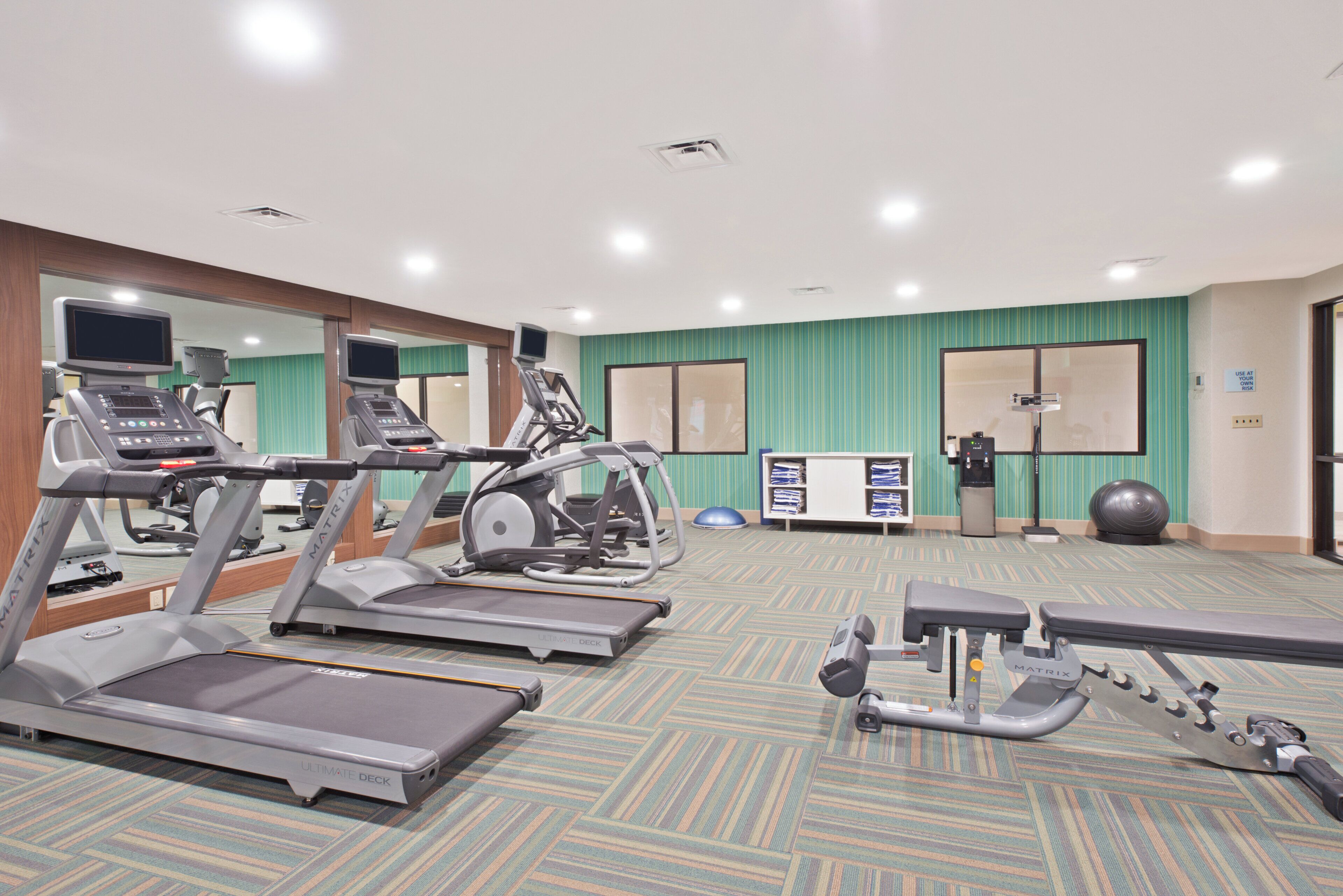 A gym with treadmills, elliptical machines, and exercise equipment.