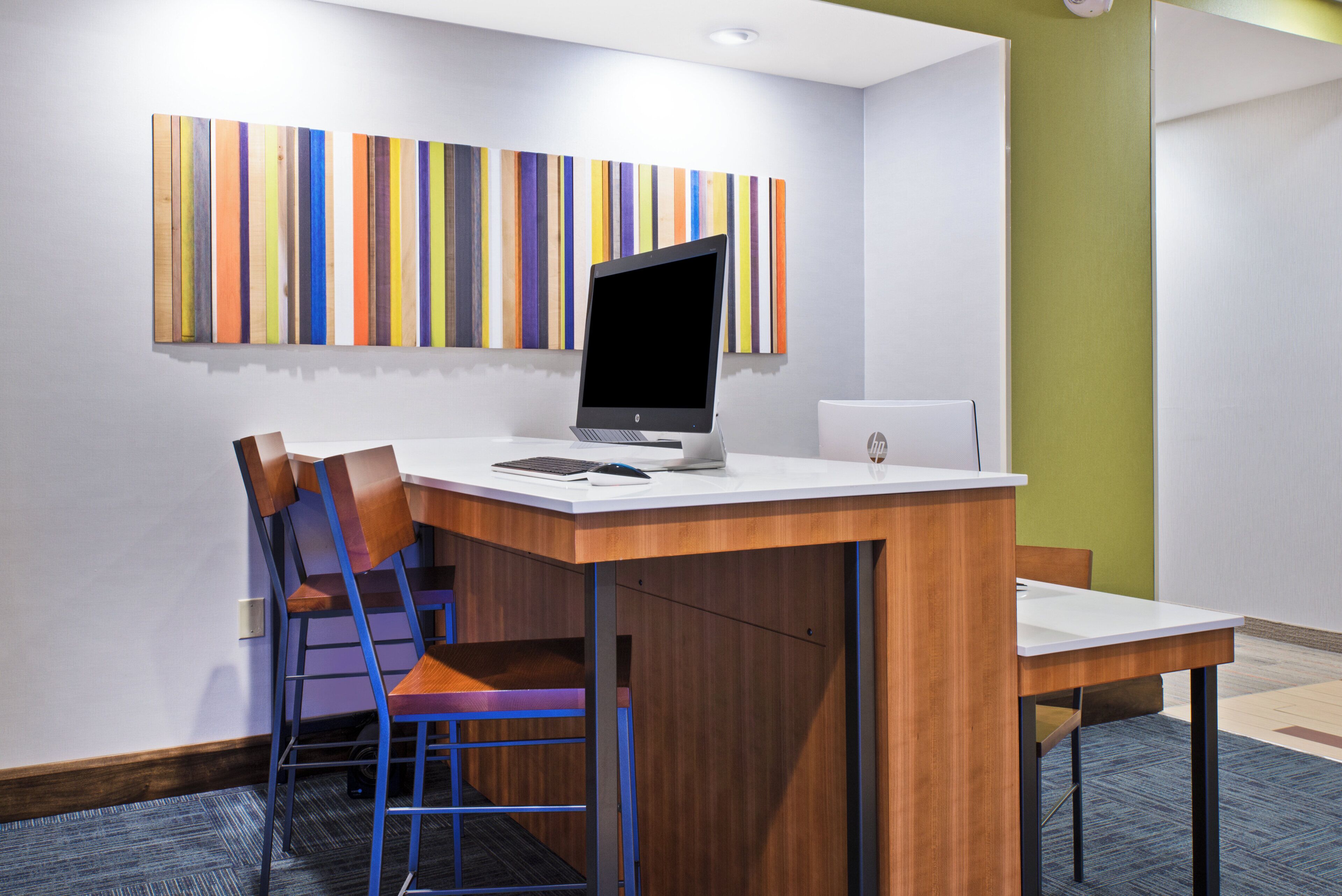 A modern office space with a desk, two chairs, a laptop, and a monitor.