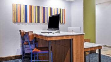 A modern office space with a desk, two chairs, a laptop, and a monitor.
