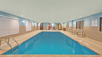 A swimming pool with a no diving sign, a lifeguard on duty sign, and a pool rules sign.