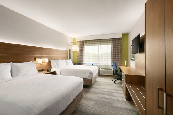 Hotelkamer met twee bedden, een bureau, een stoel, een televisie en een raam met gordijnen.