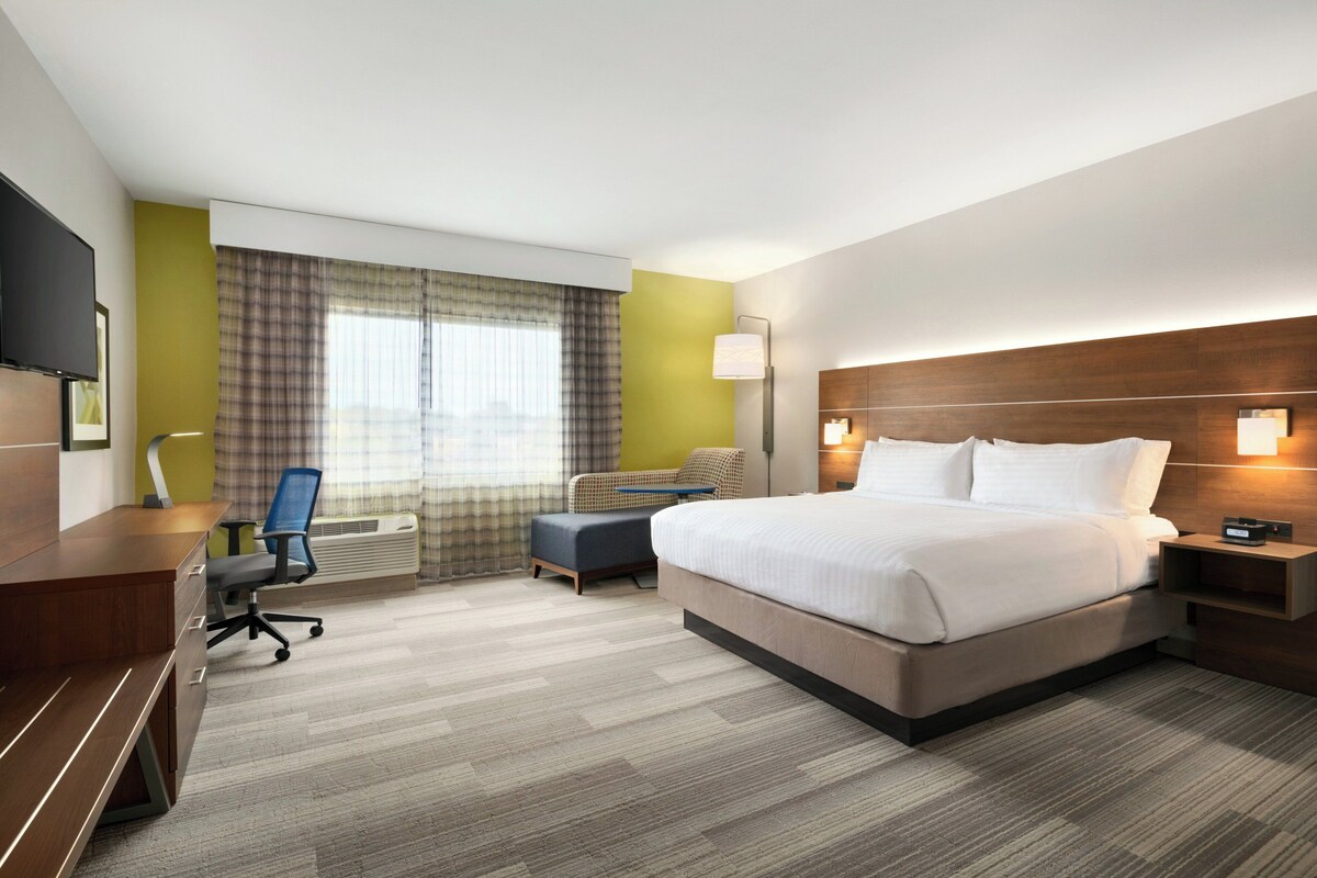 Een hotelkamer met een groot bed, een bureau met stoel, een kleine zithoek en een televisie.